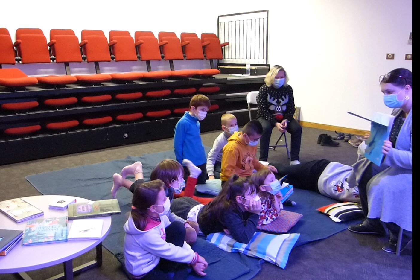 Lecture à voix haute en médiathèque Plusieurs enfants écoutent l'histoire racontée par l'animatrice